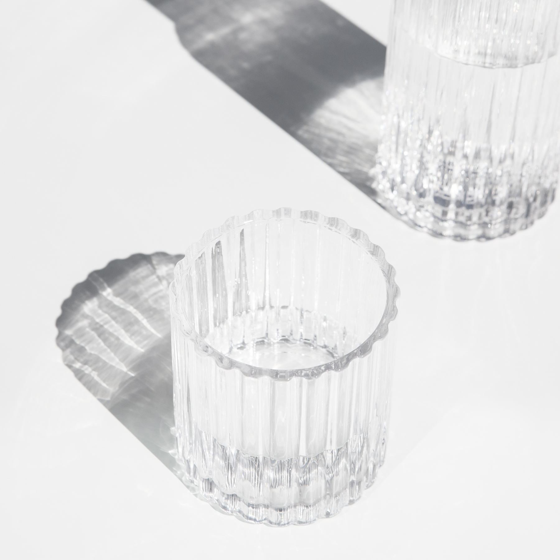 Clear ribbed glass cups arranged on a bright white surface
