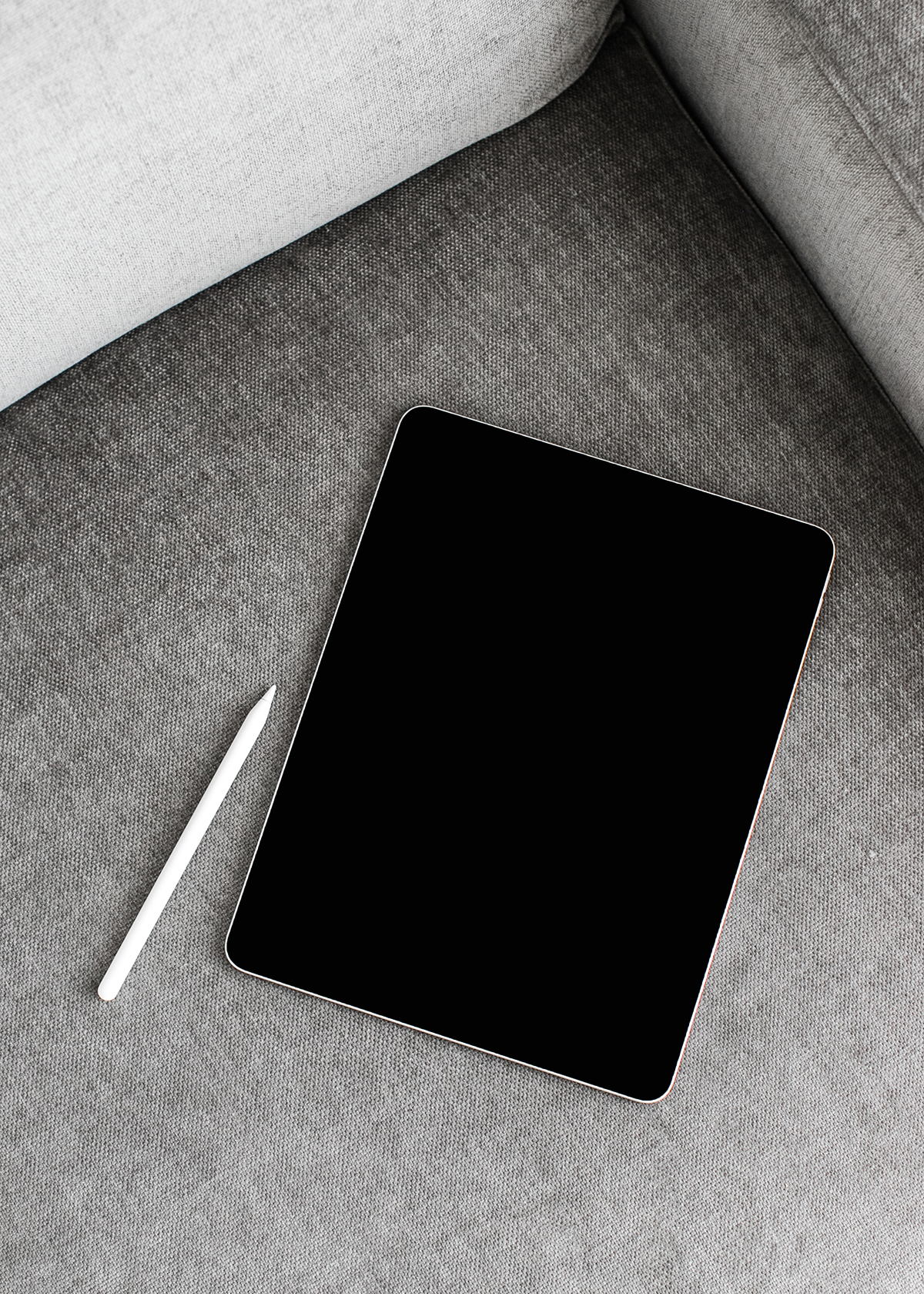 Black smartphone on a light gray sofa cushion with a white stylus