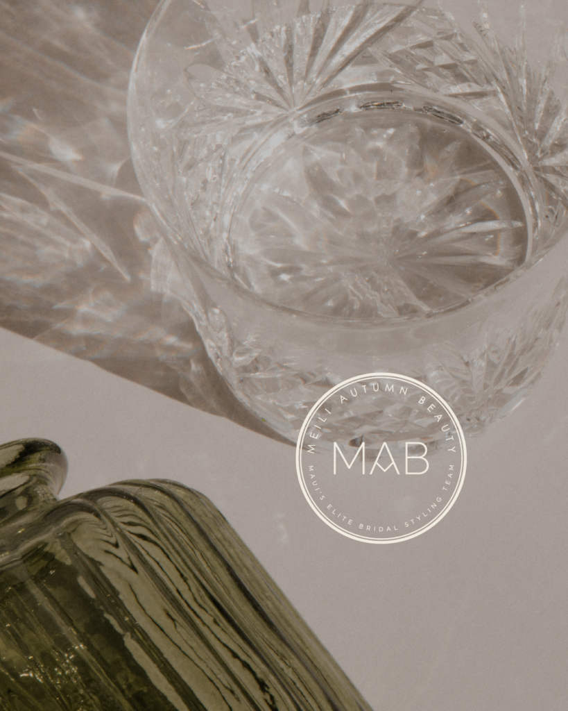 Editorial-style product photo with faceted glass and olive-green bottle on a soft neutral background