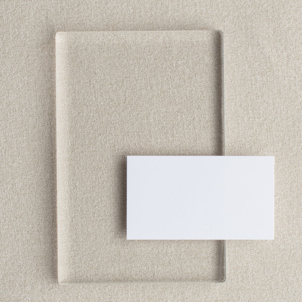 Neutral styled stock photo with a clear acrylic panel and white card on a beige textured surface