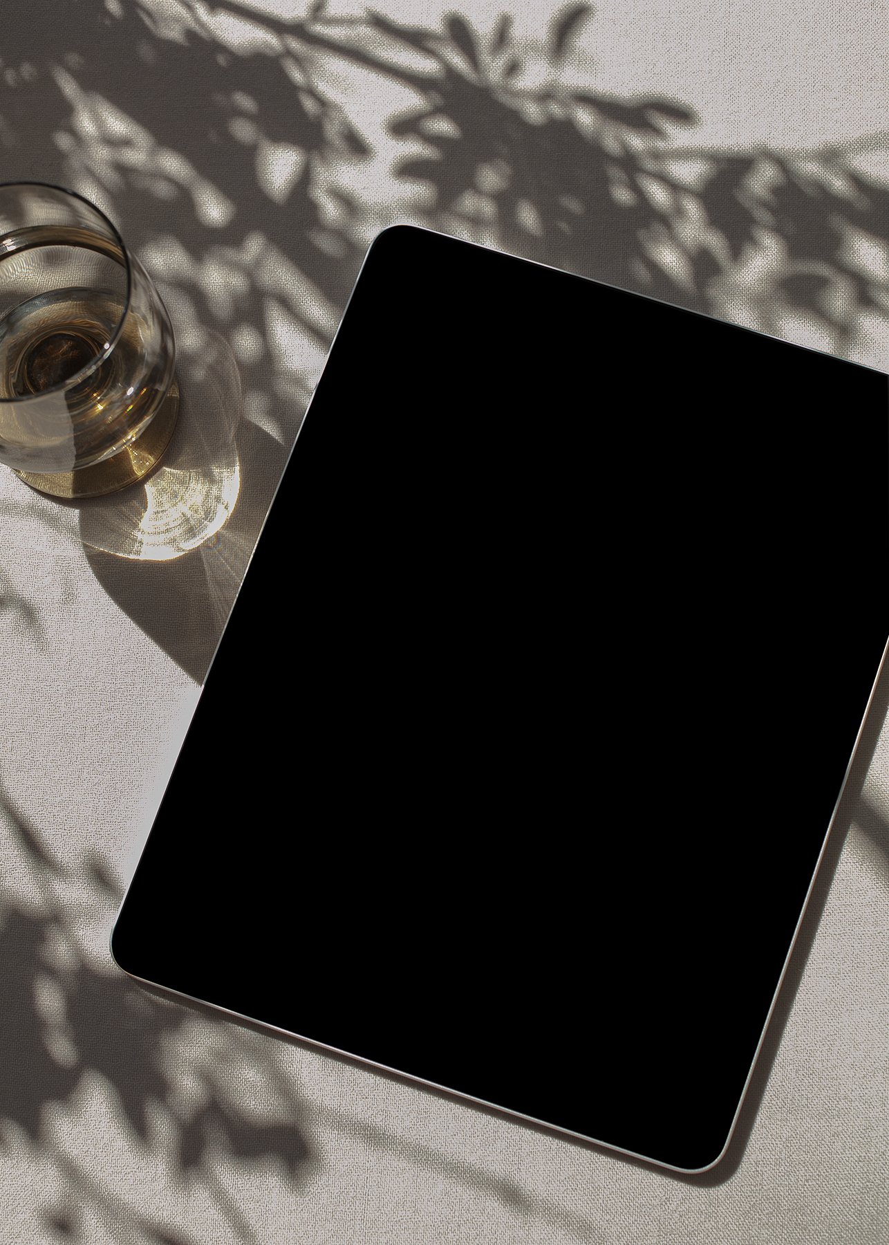 Smartphone on textured fabric with a glass vessel and soft shadows