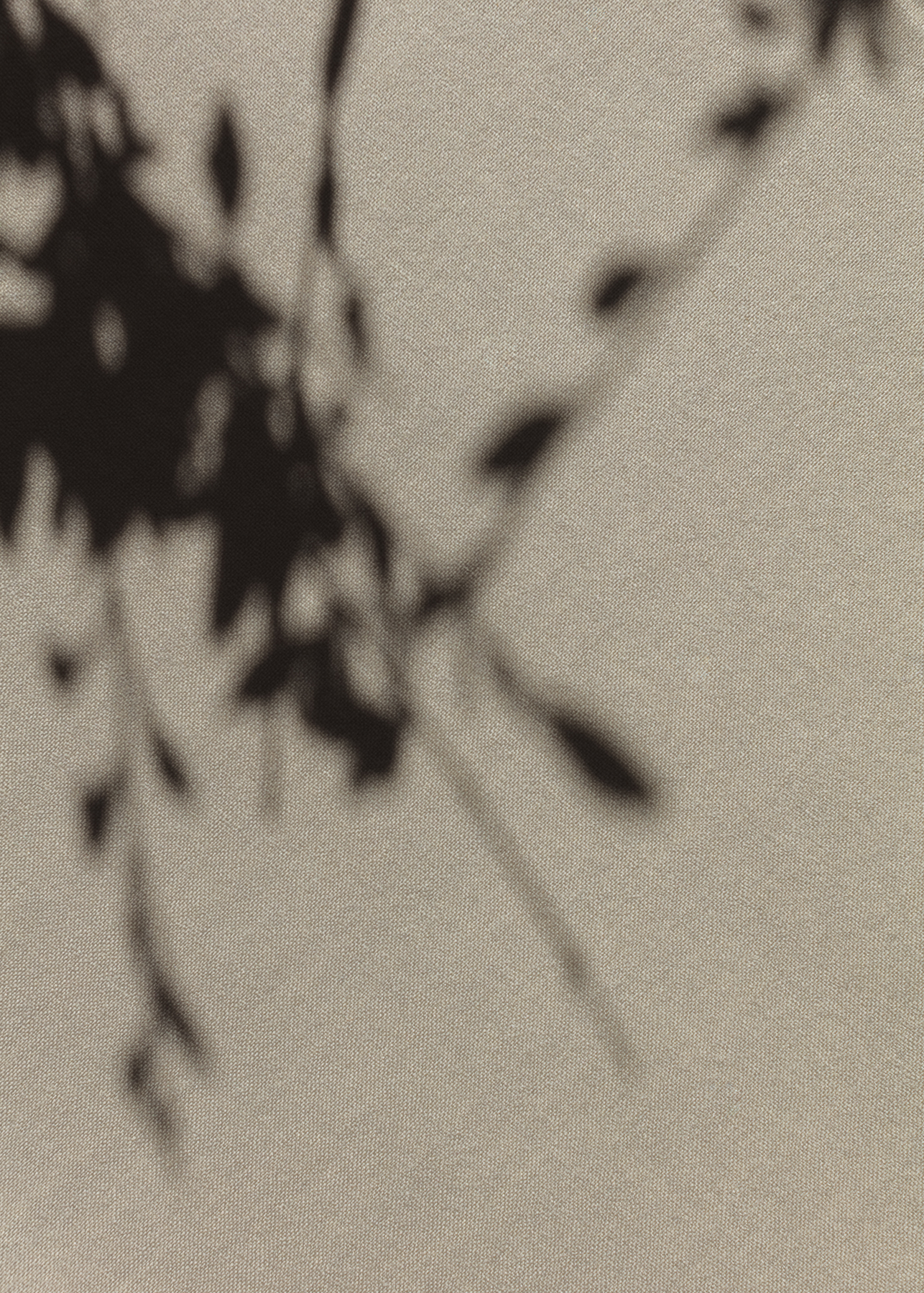 Abstract close-up of a hand and textured tan fabric with soft shadows
