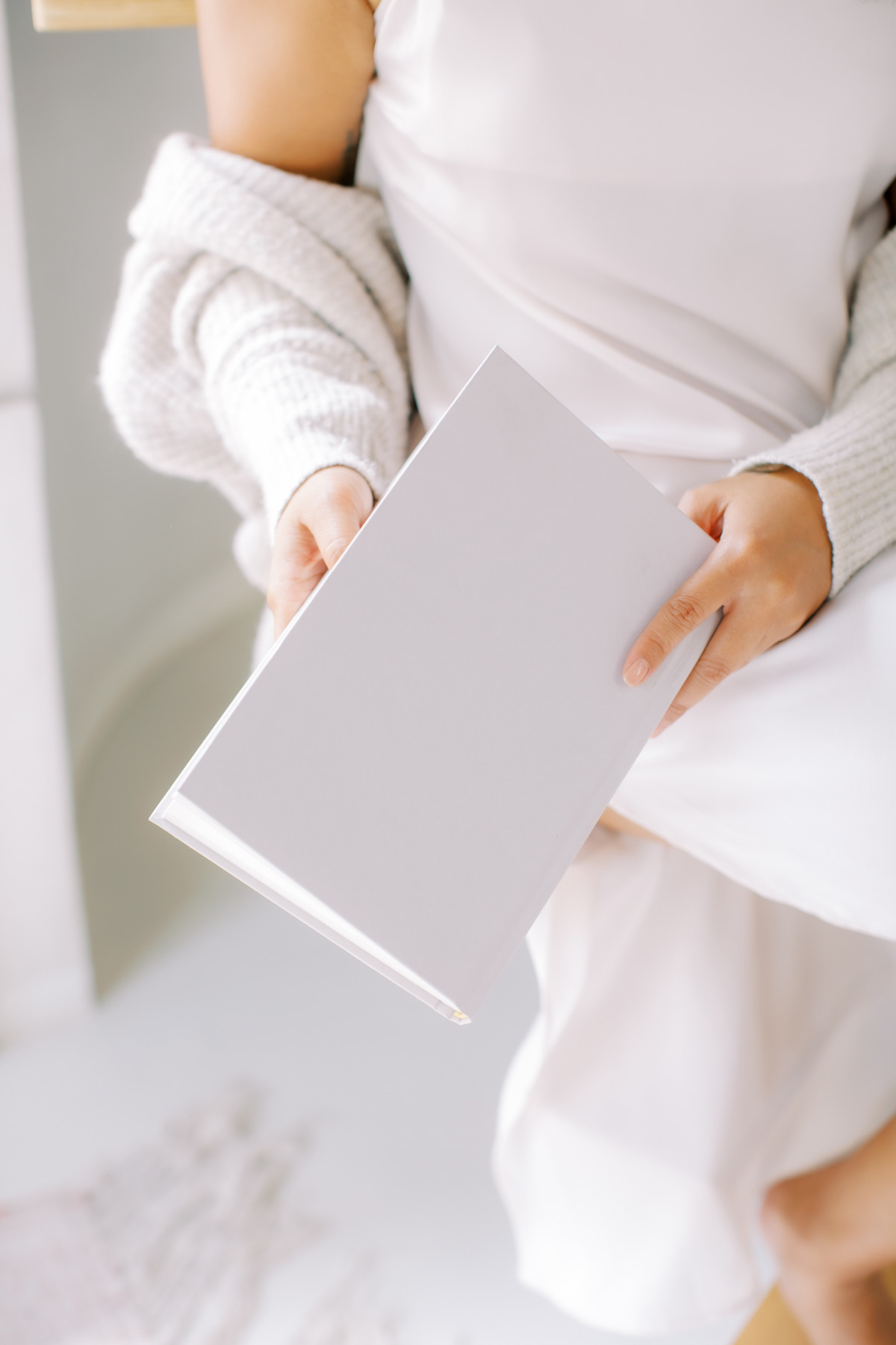 Person holding a blank light gray folder against a soft neutral background